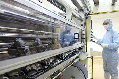 一名穿着防护服的实验室技术人员正在检查一台膜制造机器